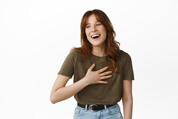 Natural happy girl with bangs, laughing and looking aside at something funny, chuckle and having fun, standing in casual clothes against white background