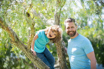 Happy family. Father and son smile sitting on tree. Family fun. Childhood and parenthood