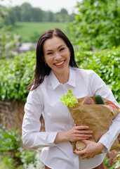 person holding  a paper bag with healthy food outside