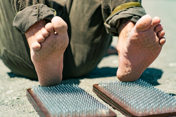 Sochi, Russia, 05.03.2021 a young stylish male yogi with tattoos stands on a sadhu board with nails