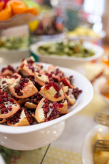 pomegranate broken in a white plate on a table with fruit.