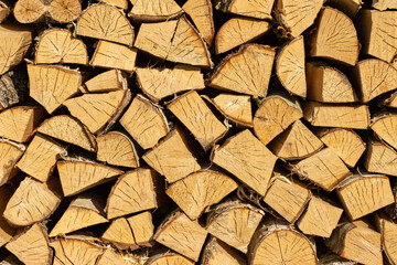 Stacked woodpile of firewood, structured wood background for design.