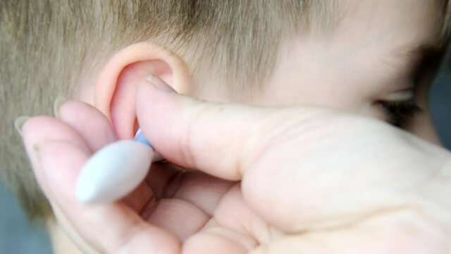 close-up ear child, kid, adult hand gently cleans the inner ear, Spiral Silicone Earwax Remover blue, modern hygiene concept, daily routine, body care