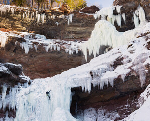 A woman boldly climbs frozen waterfall at Kaaterskill Falls New York in the winter