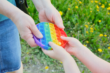 an elderly woman and a child holding an antistress toy pop it in the street, grass on the background