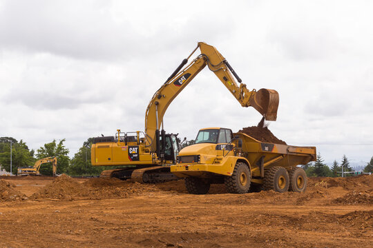 Construction Site With CAT (Caterpillar) Equipment. Excavator Loads A Truck With Soil