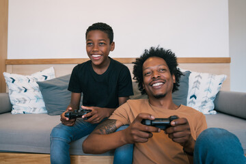 Father and son playing video games together at home.