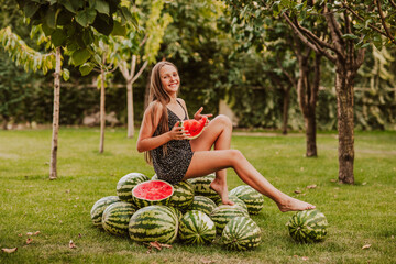 Teen girl posing with slice of watermelon in the garden with harvest. Copy space