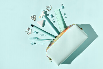 School stationery in a pencil case on a light blue background with space for text. Flat lay. Top...