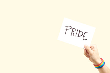 Hand with a rainbow bracelet, LGBT symbol, holding a paper with a message: pride
