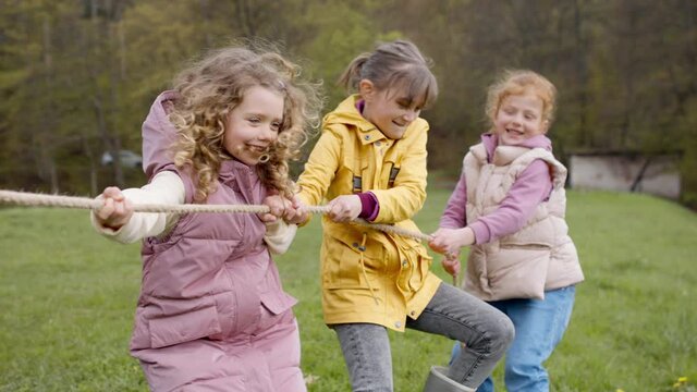 Group of school children doing rope pulling outside in nature.