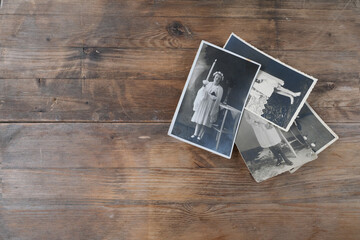 stack of old vintage monochrome photographs on photographic paper on natural wood background, concept of genealogy, the memory of ancestors, family tree, nostalgia, childhood, remembering