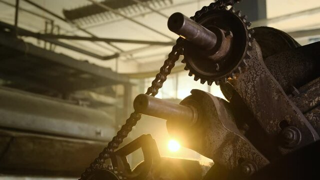 Old Rusty Gears With Chain In Abandoned Vintage Factory. Light Enters Through Holes In Cogwheel. Slow Close Up Footage In Old Vintage Not Working Plant.