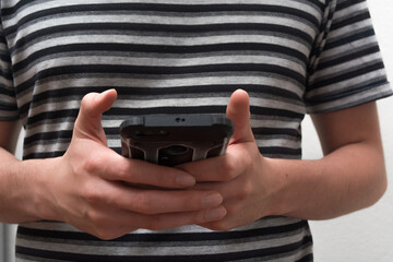 Hands holding a smartphone or mobile phone using social media apps to chat. striped shirt clothes in the background