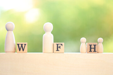 Work from home or initial is  W F H  word on wooden block on blue cloth with green light bokeh background as new normal because of COVID-19 virus.