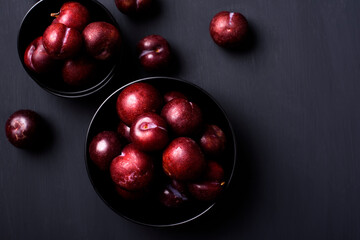 Japanese or Chinese red plum fruit in a bowl on black background, Top view