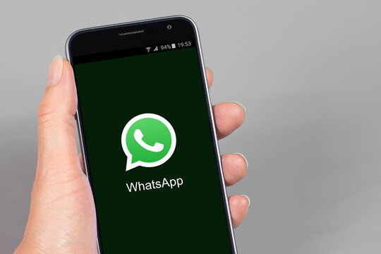 Main de femme tenant un téléphone portable avec l'application WhatsApp