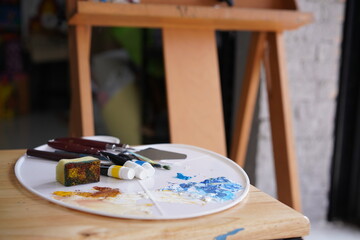Acrylic sea and beach painting on drawing stand with palette and brush. Blue wave on golden sand hand painting with brush and knife palette technique. Art on canvas.