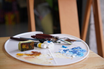 Acrylic sea and beach painting on drawing stand with palette and brush. Blue wave on golden sand hand painting with brush and knife palette technique. Art on canvas.