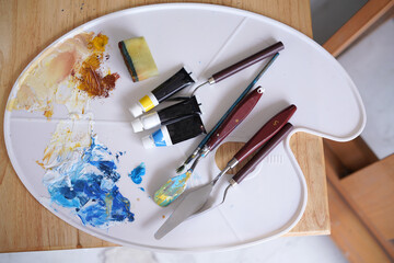 Acrylic sea and beach painting on drawing stand with palette and brush. Blue wave on golden sand hand painting with brush and knife palette technique. Art on canvas.
