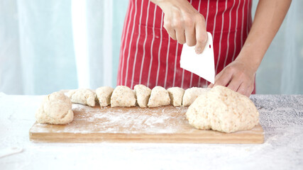 Whole wheat bread from homemade whole grain dough made by woman with red apron. Healthy pastry with many grains.