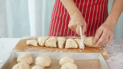 Whole wheat bread from homemade whole grain dough made by woman with red apron. Healthy pastry with many grains.