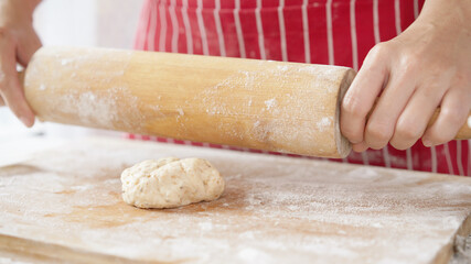 Whole wheat bread from homemade whole grain dough made by woman with red apron. Healthy pastry with many grains.