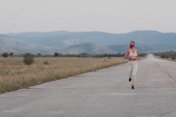 Obraz premium Determined fitness woman in short clothes wearing red protective face mask running outdoors in the city during coronavirus outbreak. Covid 19 and physical jogging activity sport and fitness.