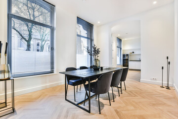 Luxury apartment dining room with parquet and black dining set against white kitchen in open plan...