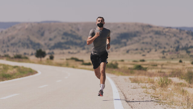Young man and woman in protective masks running and doing exercises outdoors in the morning. Sport, Active life Jogging during quarantine. Covid-19 new normal. High quality photo. Selective focus.