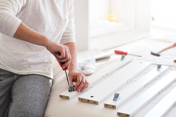 Woman using screwdriver to assemble furniture