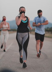 Multiethnic runners group wear face masks running keep social distance outdoor. Fit healthy diverse team wears sportswear jogging in evening on nature sports track distancing for safety.