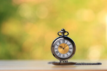 Vintage pocket elegent watch with green bokeh background as retirement time pass. Classic retro...