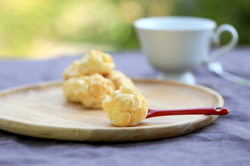 Choux cream, small fluffy creamy yummy vanilla inserted in round dessert as cold fresh sweet on wood plate.