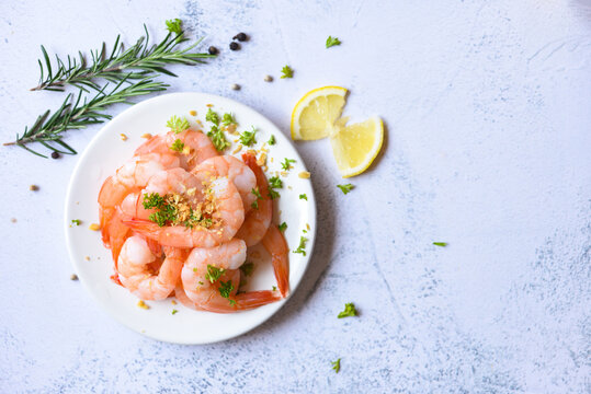 Garlic shrimp peeled on white plate background dining table food, Fresh shrimps prawns seafood lemon with herbs and spice, top view