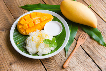 Ripe mango rice cooked with coconut milk, Sticky rice summer tropical fruit food Asian Thai dessert sweet mango peel and sliced on banana leaf and fresh mint leaves - 438014543