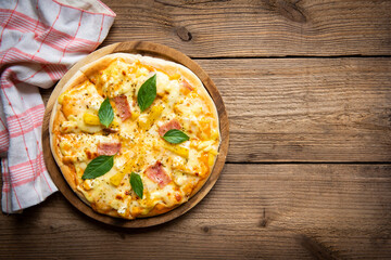 Tasty pizza homemade italian food style, pizza cheese ham and pineapple fruit cooking ingredients basil on wooden background, Top view of pizza cheese italian food style. Flat lay