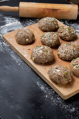 Brown whole wheat bread with multi grain in preparing to get dough for baknig as healthy bread on black background with wood board and roll. Sesame and seeds on bread.