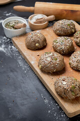 Brown whole wheat bread with multi grain in preparing to get dough for baknig as healthy bread on black background with wood board and roll. Sesame and seeds on bread.