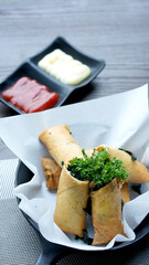 Spinach cheese Chinese deep fried with thin rice flour as roll on plate. Cut in half of crispy vegetable with ketchup dip and mayonaise. Vietnamese and fusion Italian spring roll menu.