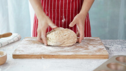 Whole wheat bread from homemade whole grain dough made by woman with red apron. Healthy pastry with many grains.