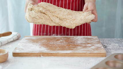 Whole wheat bread from homemade whole grain dough made by woman with red apron. Healthy pastry with many grains.