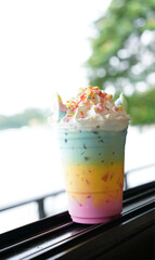 Unicorn beverage, fusion cute colorful milky menu with marchmallow. Three color in multi layers with ice in plastic cup with whipped cream.