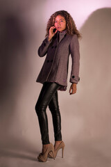 vertical portrait of a curly model wearing a jacket, black pants and heels