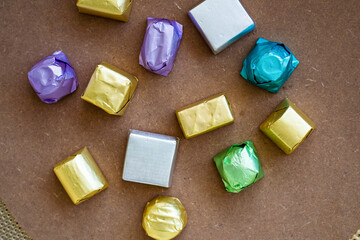 wrapped luxury chocolates in various colours for different flavours on a brown background.