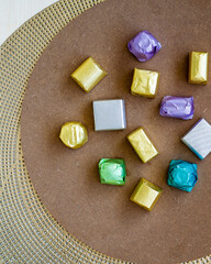 wrapped luxury chocolates in various colours for different flavours on a brown background.