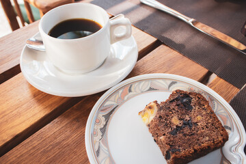 Cup of black coffee and banana bread loaf. Breakfast in hotel. Morning dessert. Hot beverage with pastry. Espreso with biscuit. Homemade banana bread with hot drink. Sweet food.  