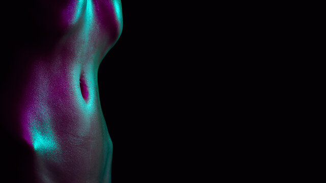 Sexy naked wet body of a girl with water drops. A skinny belly in the neon light