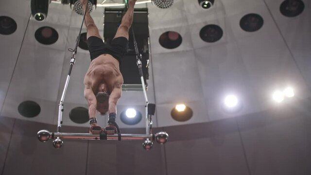Acrobatic bearded man standing on hands upside down on performance construction