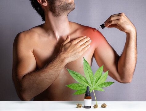 CBD oils designed for athletes to treat muscle discomfort, man applying oil made from cannabis extract over injured shoulder, medical pain treatment. Isolated on gray background